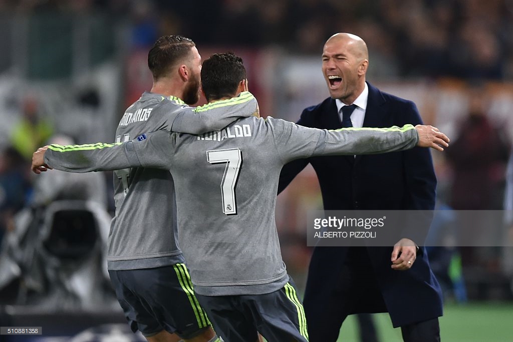 Real Madrid's Portuguese forward Cristiano Ronaldo (C) celebrates with Real Madrid's defender Sergio Ramos and Real Madrid's French coach Zinedine Zidane after scoring during the UEFA Champions League football match AS Roma vs Real Madrid on Frebruary 17, 2016 at the Olympic stadium in Rome. AFP PHOTO / ALBERTO PIZZOLI / AFP / ALBERTO PIZZOLI